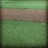 A textured surface featuring a path-like strip of coarse brown gravel running horizontally through two areas of vibrant green artificial grass.