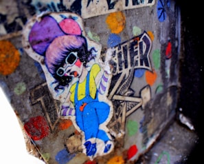 A colorful graffiti sticker depicts a cartoon-style character wearing oversized sunglasses, a purple hat, a yellow shirt, and blue overalls. The background features a mix of vivid colors and abstract shapes, including polka dots, with the word 'TRENDSETTER' partially visible.