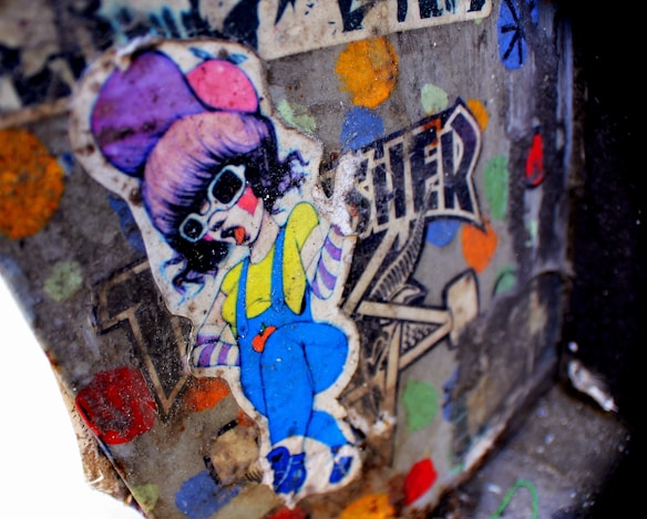A colorful graffiti sticker depicts a cartoon-style character wearing oversized sunglasses, a purple hat, a yellow shirt, and blue overalls. The background features a mix of vivid colors and abstract shapes, including polka dots, with the word 'TRENDSETTER' partially visible.
