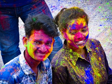 Fred and Leslie making silly faces with colorful face paint at a school reunion.