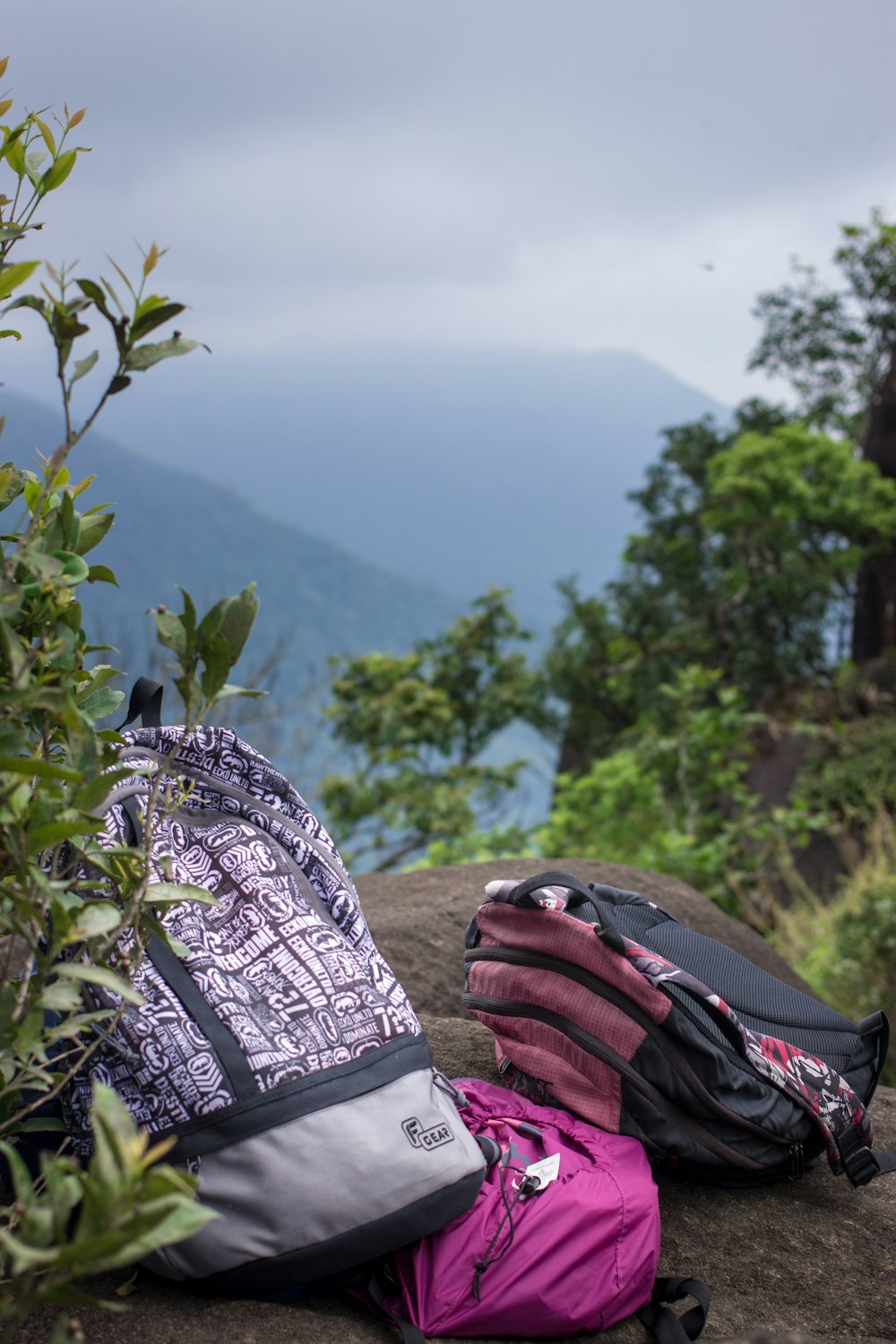 three backpacks on gray rock under cloudy sky during daytime