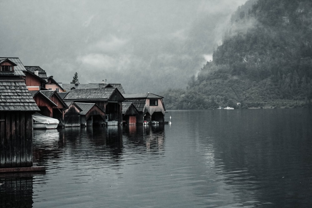 brown houses beside body of water and mountains
