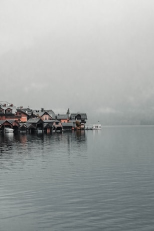 A quiet lakeside village reflecting in still water under a cloudy sky.