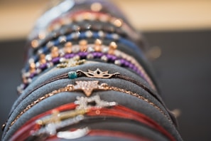 Close-up of hands mixing colorful bracelets and rings on a bright background.