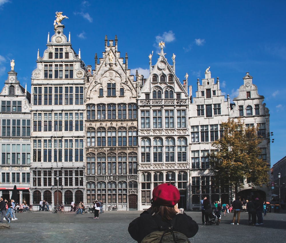 woman taking photo of white concrete buildings during daytime