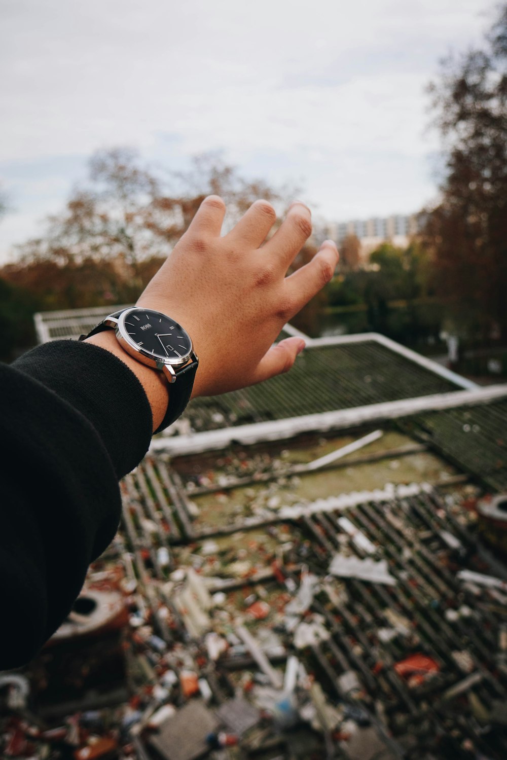 person wearing black jacket and round silver-colored and black analog watch during daytime