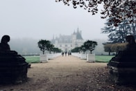 four person walking towards concrete house during foggy daytime
