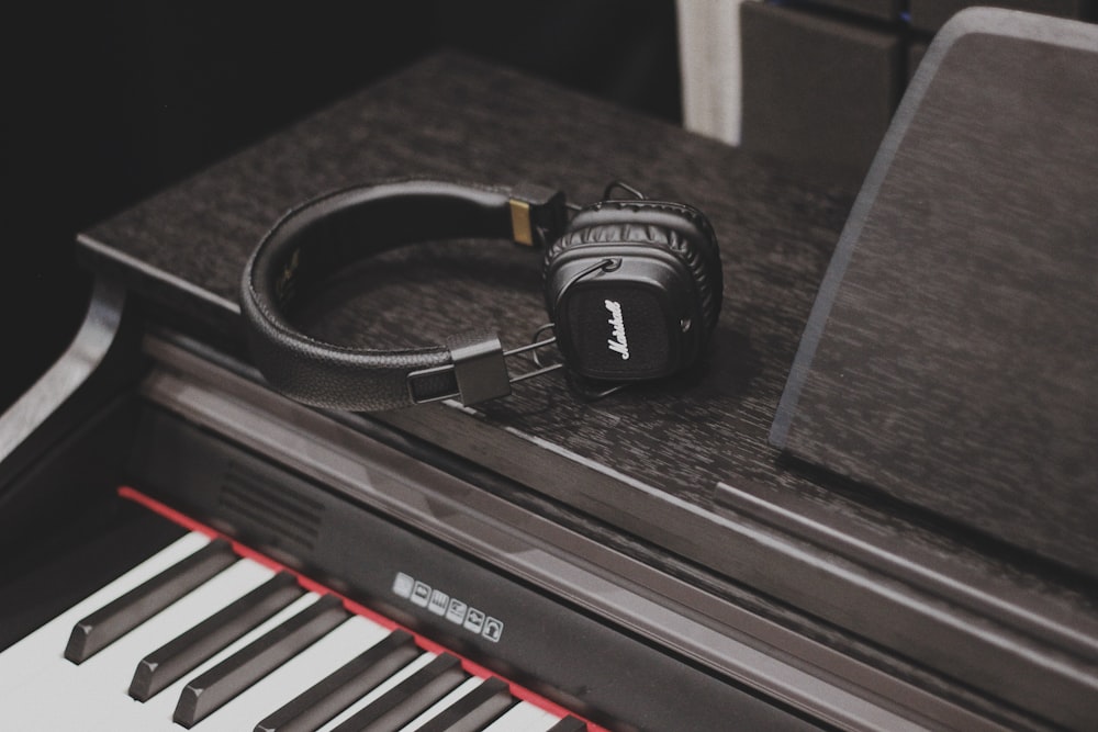 black and white Bluetooth headphones on top of black piano