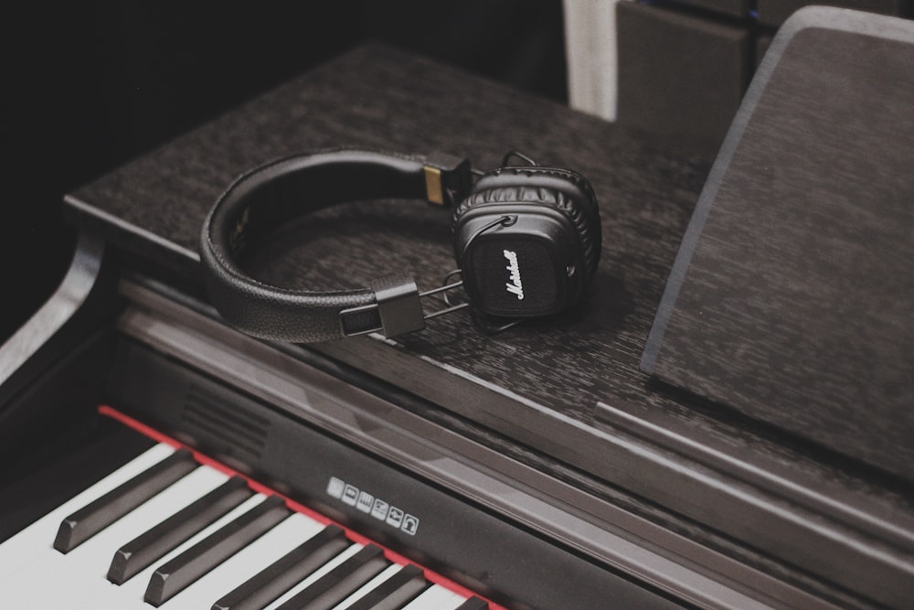 검은색 피아노 위에 있는 흑백 Bluetooth 헤드폰