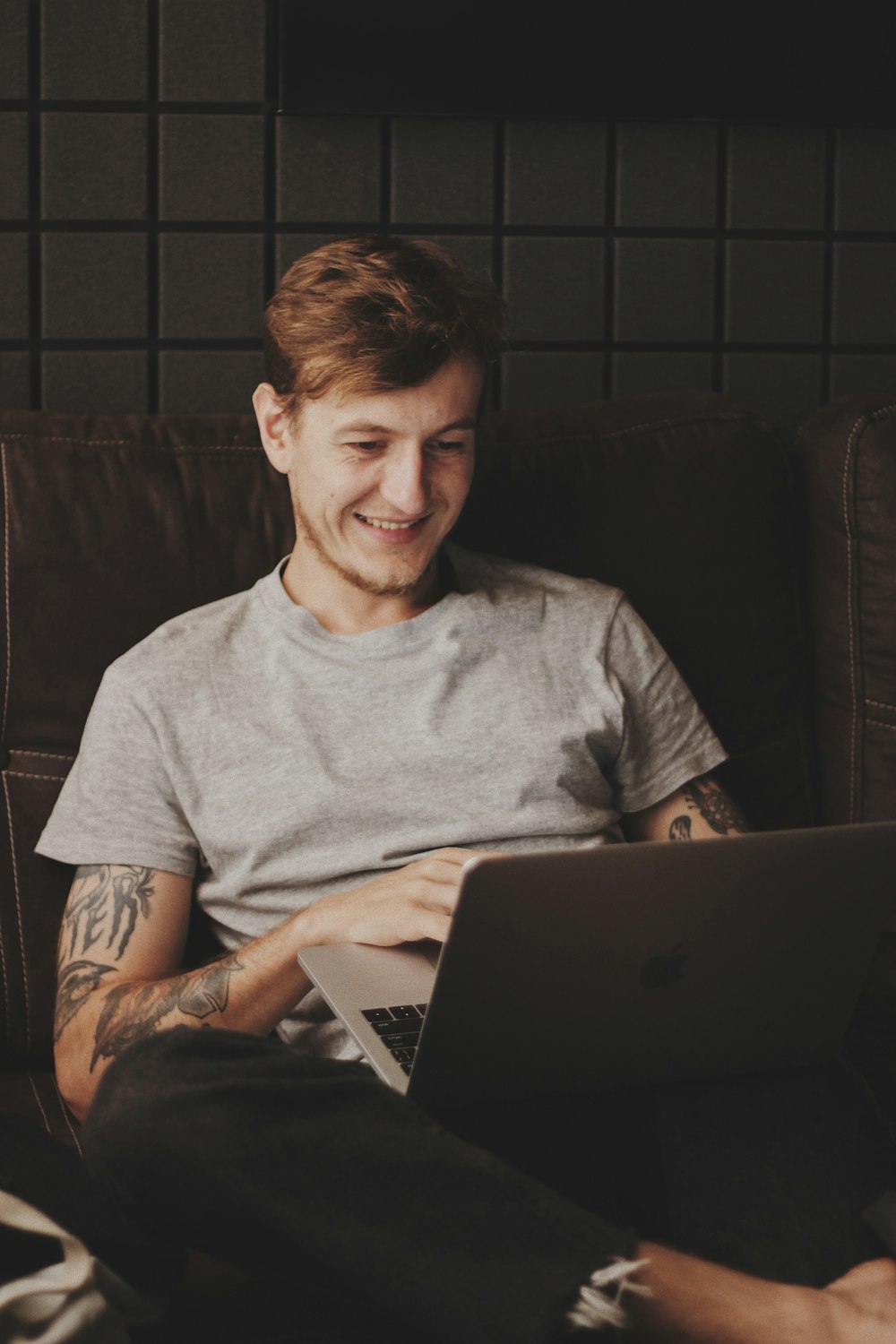 man sitting facing silver MacBook inside room