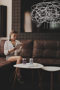 woman sitting on tufted brown padded sofa