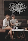 young man and lady sitting on sofa using MacBook