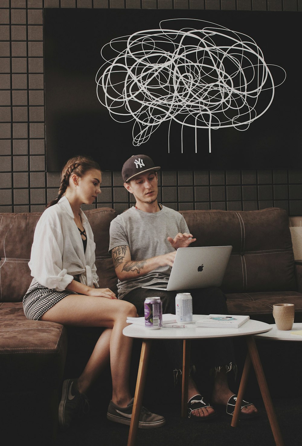 man and woman sitting on sofa using MacBook