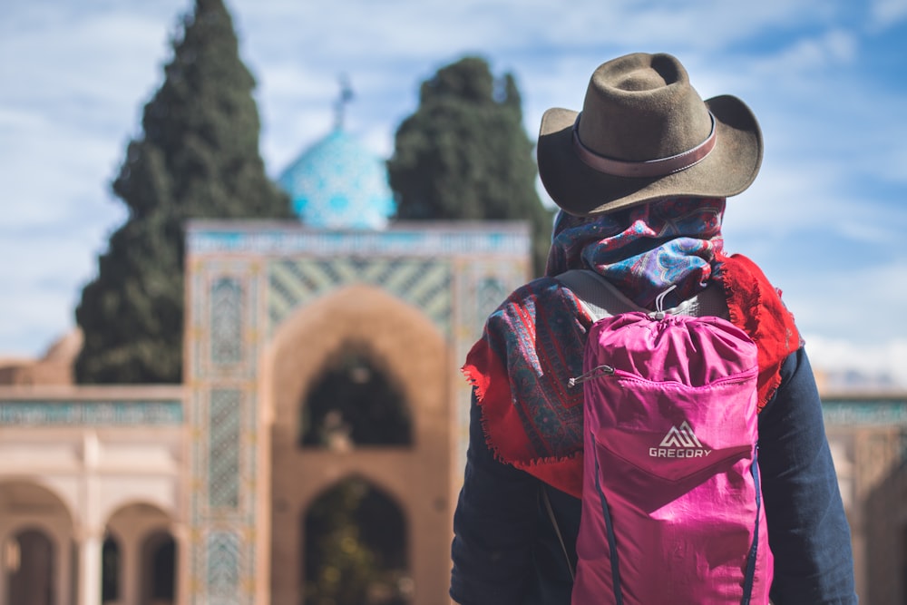 person wearing brown hat and carrying pink backpack