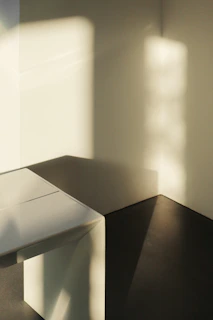 Sunlit minimalist studio corner with warm gold accents and soft shadows
