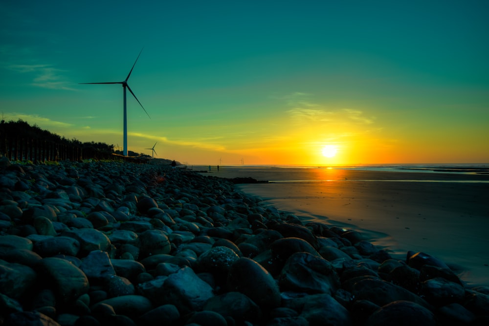 rocks near body of water and wind turbines