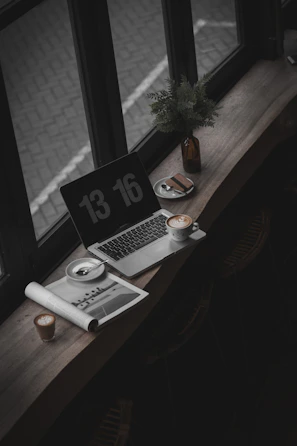 A cozy morning desk setup with a laptop, coffee cup, and soft sunlight streaming in