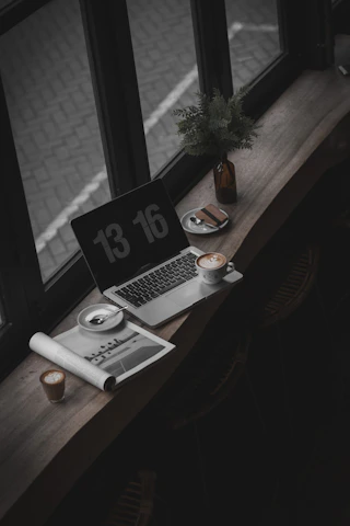 A cozy workspace with a laptop, watch magazines, and a cup of coffee.