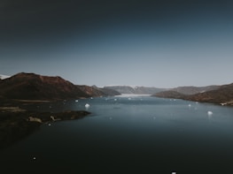 Sunset view over a peaceful fjord with snow-capped mountains in the distance.