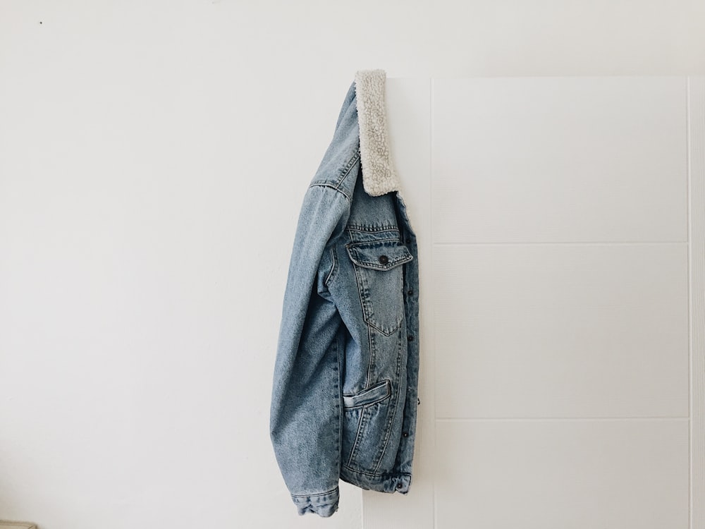 blue washed jacket hanging on white door