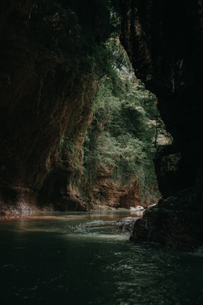 calm body of water inside cave at daytime