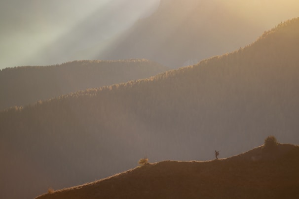 A panoramic view of Mount Halgurd at sunrise, with a lone hiker standing on a ridge.