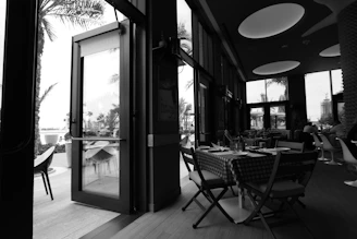 Black and white photo of a modern restaurant interior with elegant table settings.