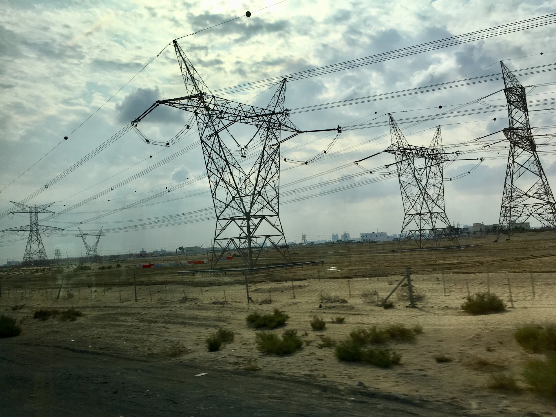 Dynamic view of high-voltage power transmission towers stretching across a desert landscape under a clear sky.