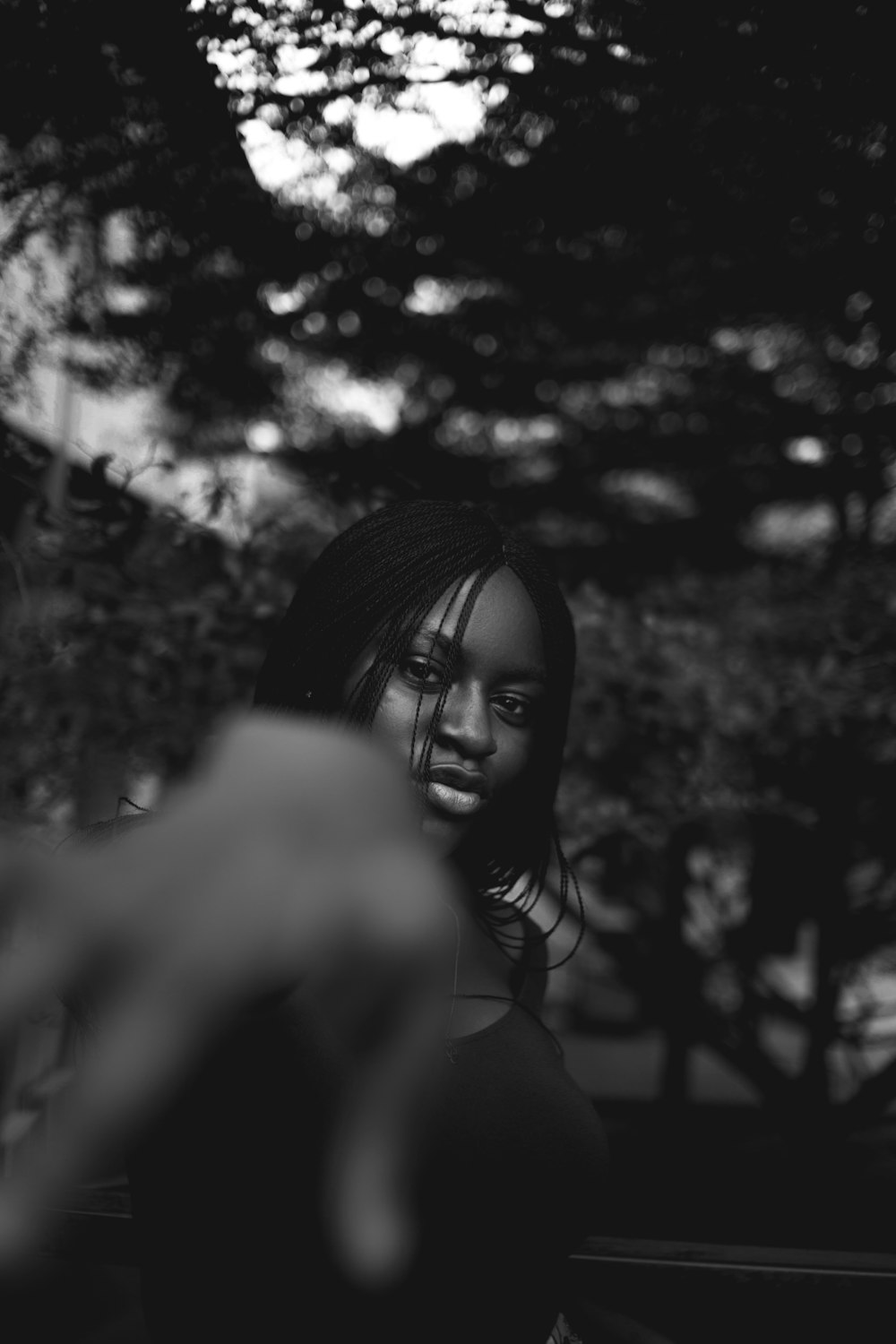 greyscale photo of woman standing near trees