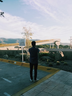 A person taking photos of a vacant land lot under clear sky.