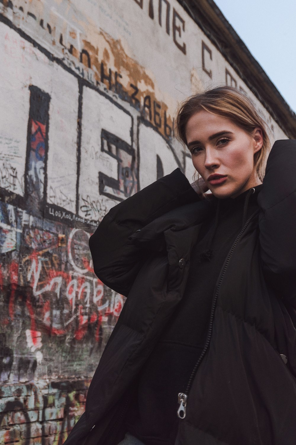 woman standing beside wall filled with graffiti