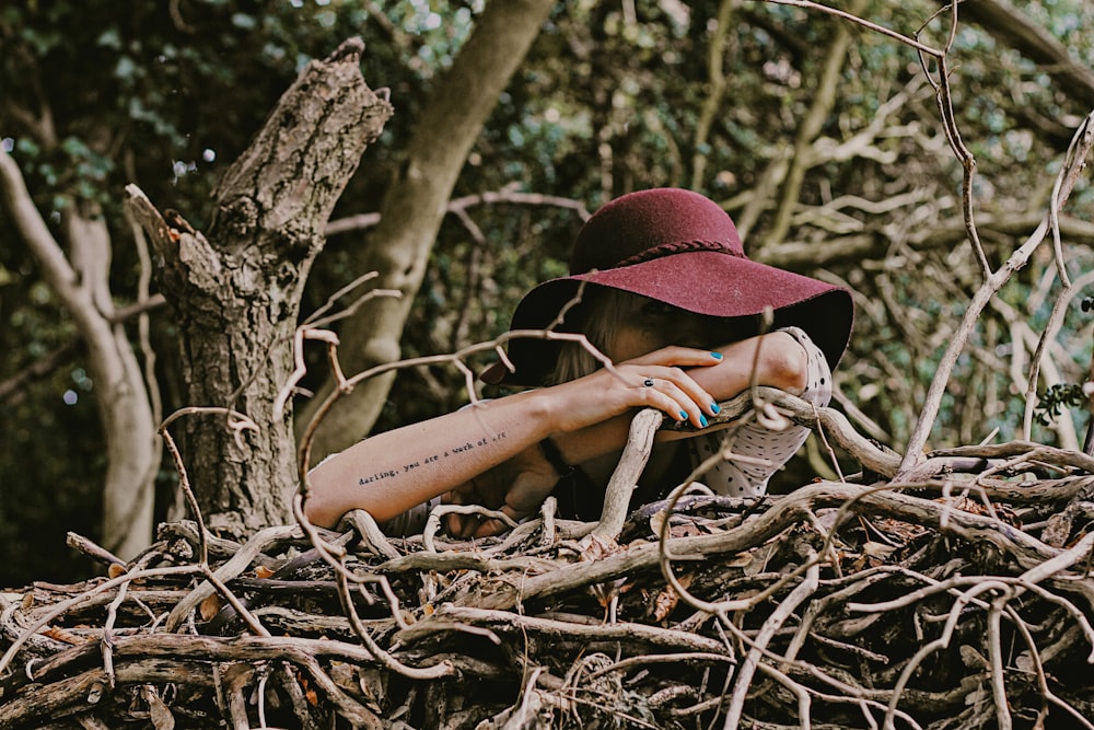 woman wearing red sun hat surround by brown twig