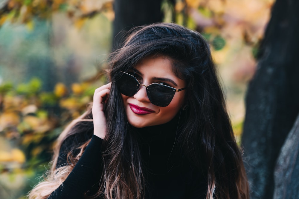 smiling woman wearing black framed sunglasses outdoor during daytime