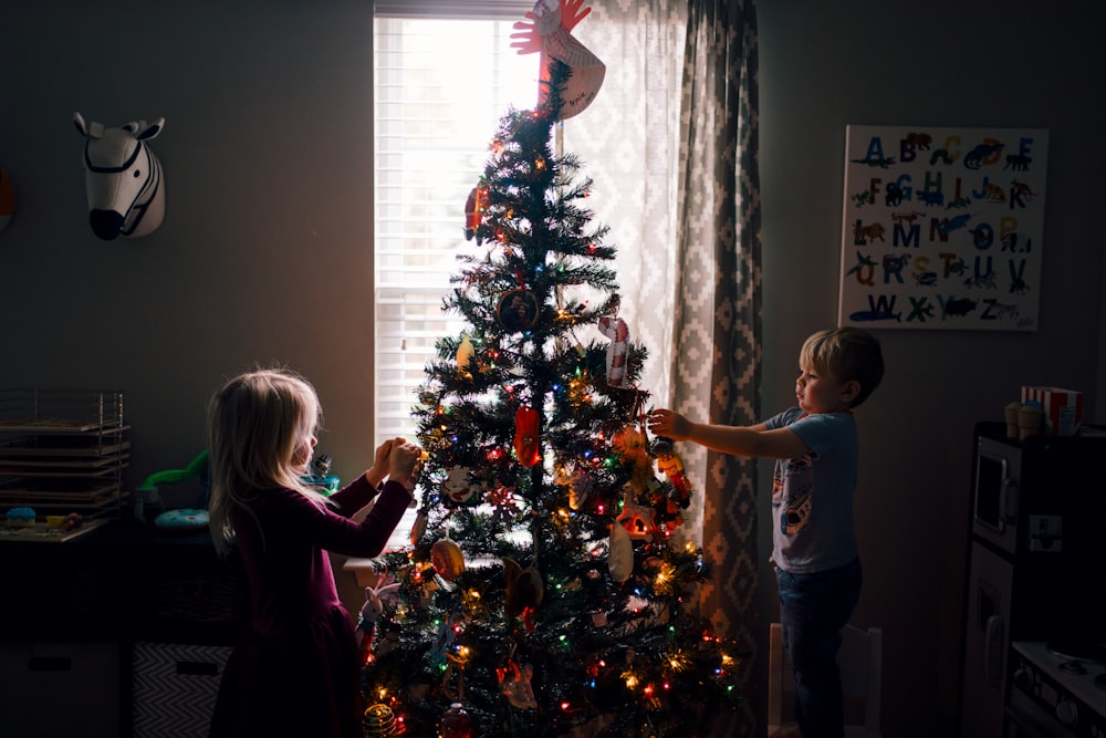 Mädchen und Junge stehen in der Nähe des Weihnachtsbaums