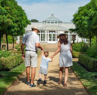 woman and man holding child while walking leading to house