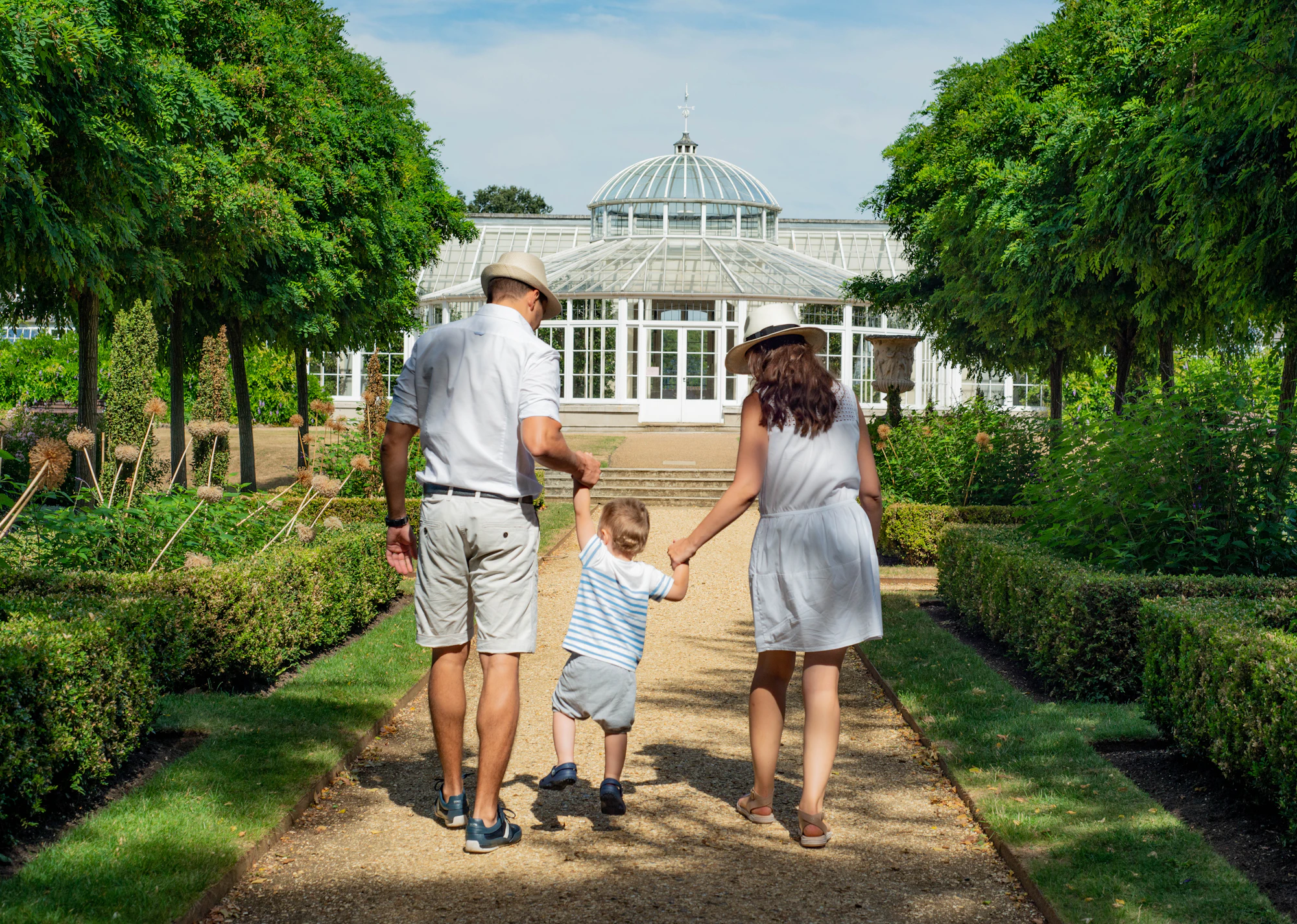 A family walking together, holding their child's hands
