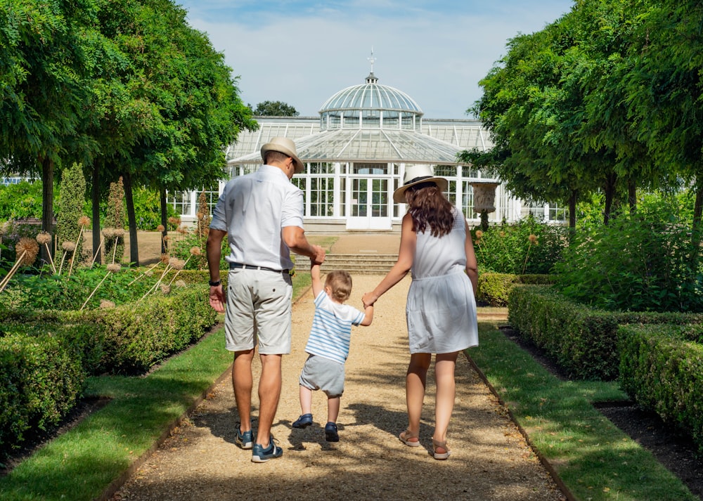 woman and man holding child while walking leading to house