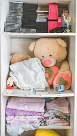 A neatly arranged shelf with eco-friendly baby toys and soft blankets in calming green and beige shades.
