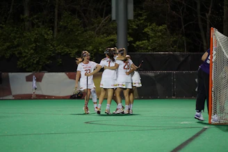 A group of smiling girls in softball gear celebrating a team victory on the field.