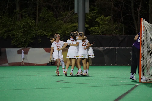 A group of smiling girls in softball gear celebrating a team victory on the field.
