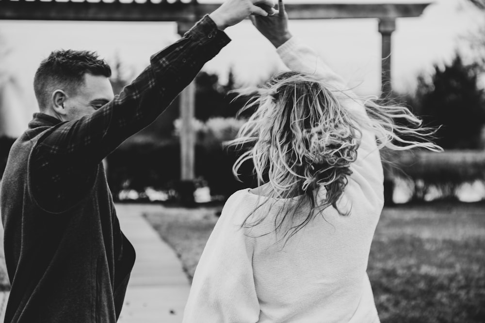 grayscale photography of man and woman dancing outside