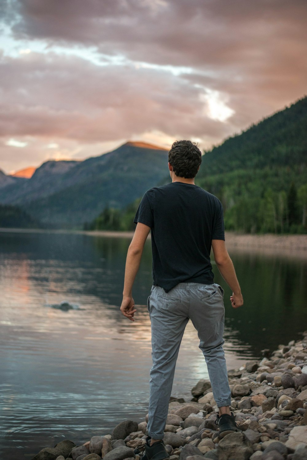man standing on rock near lake