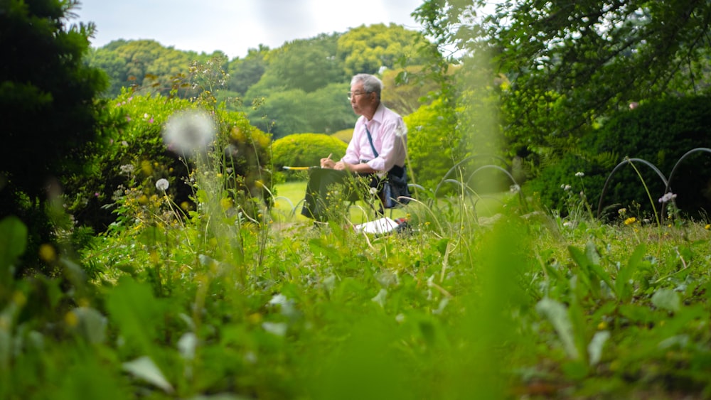 man writing while sitting on green grass