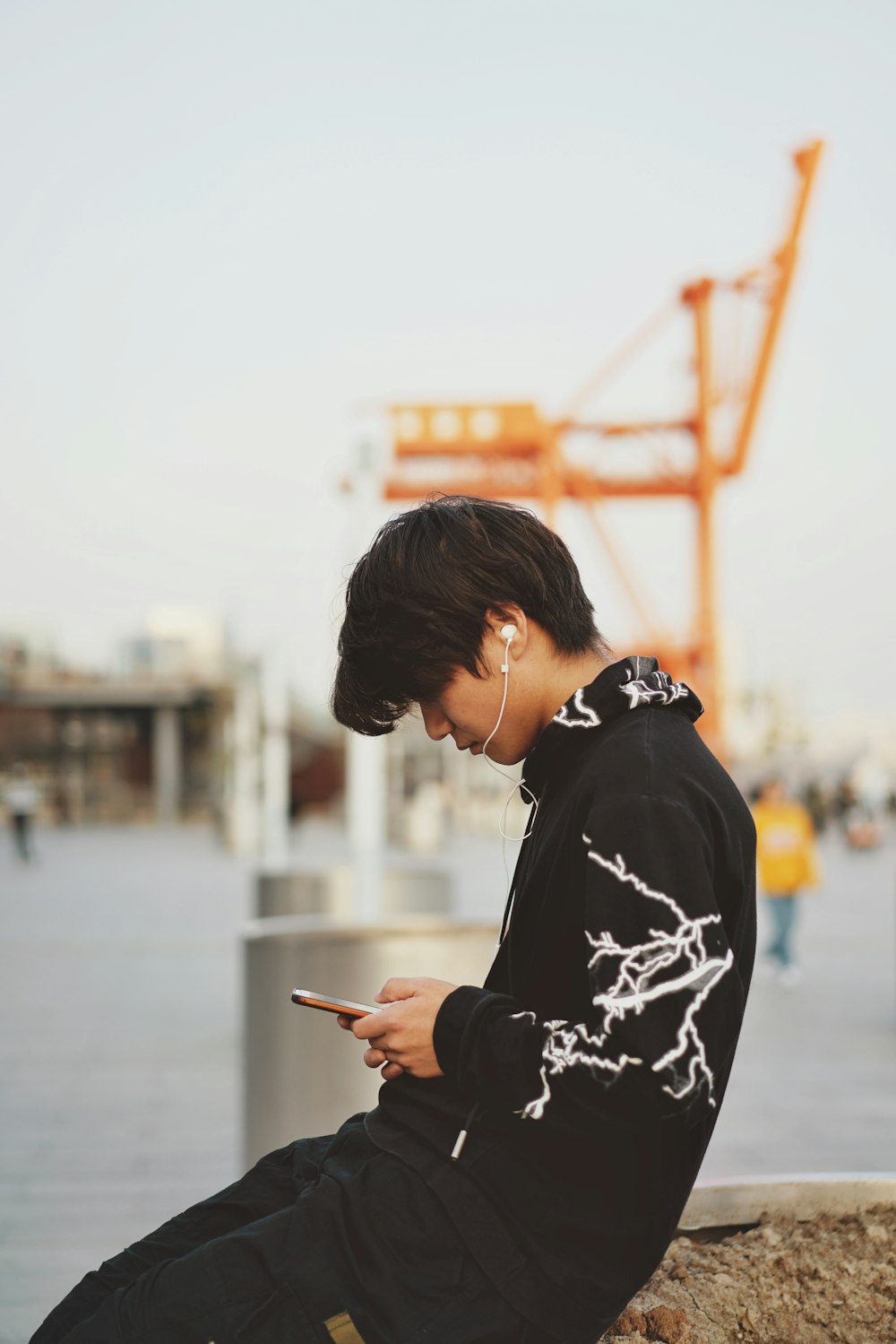 man holding phone sitting on brown wall