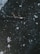 Aerial view of a sailing ship navigating through a dark, icy sea scattered with snow-covered icebergs and ice fragments. The ship is surrounded by numerous small and large pieces of ice, presenting a challenging landscape.