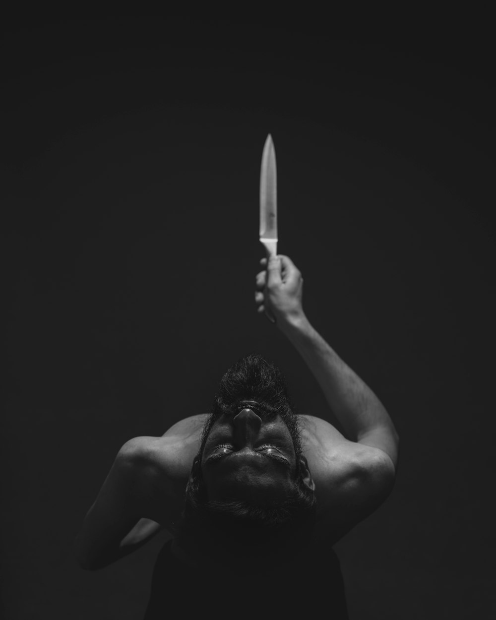 Fotografía en escala de grises de un hombre sosteniendo un cuchillo