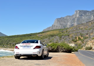 A sleek Mercedes van parked by the Adriatic coast with mountains in the background.