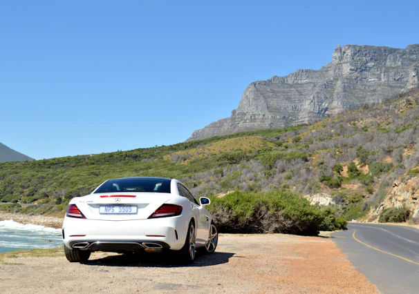 Side profile of a Mercedes parked on a scenic road with mountains in the background.