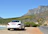Elegant black Mercedes Classe V parked by a sunlit Sardinian coastline.