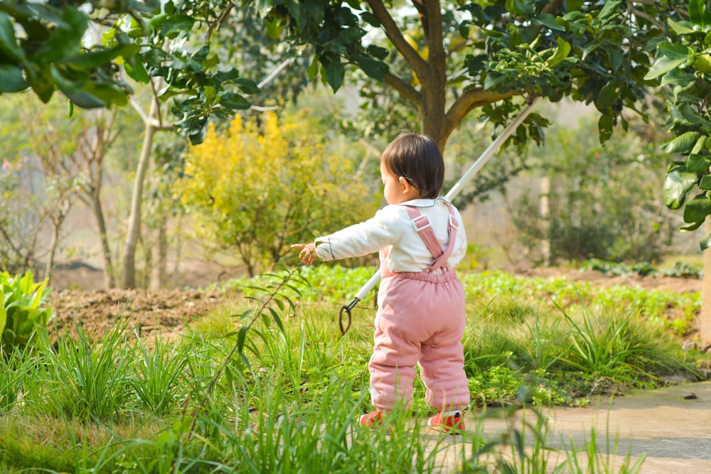 boy wearing pink overall pants holding white stick